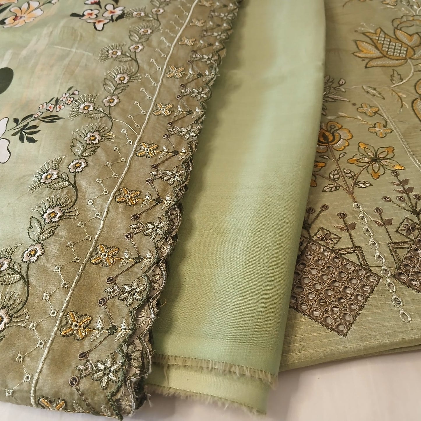 closeup detailed embroidery on pista green doria lawn shirt fabric